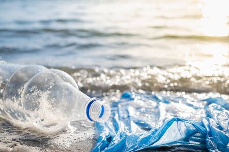 Plastic bag and bottles on the beach, seashore and water pollution concept. Trash (empty food...