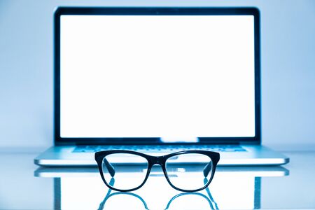 Computer eyeglasses in front of a laptop, close-up view. Blue light blockers and laptop in bright background, eye fatique problem conceptの写真素材