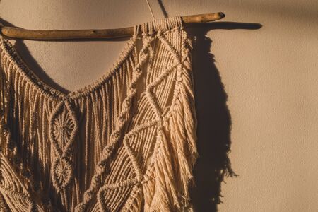 Detailed shot of the macrame wall hanging. DIY boho wall tapestry hanging on the wall in the morning sunの写真素材