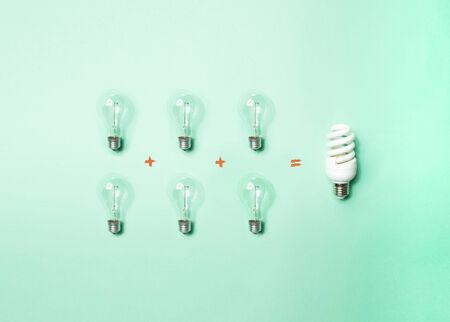 Tungsten light bulbs and energy-saving bulb on green background. Concept of energy saving.の写真素材