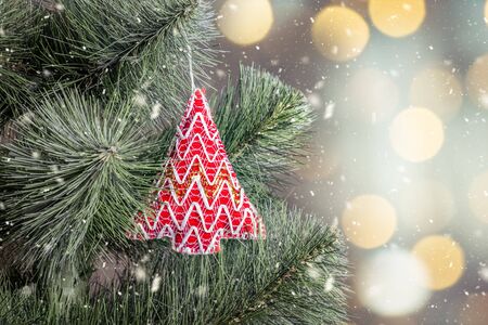 Toy Christmas decoration on fir tree branch, festive snowy background with bokeh. New Year and Christmas holidays concept.の写真素材