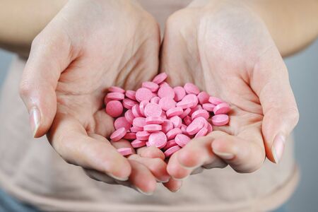 Pile of red pills in human hands. Concept of taking too much medicine, overdose or suicide attempt by taking prescription drugsの写真素材