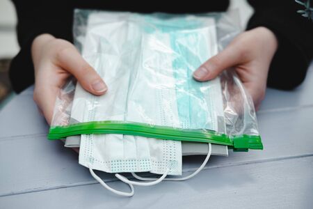 Respiratory masks in a package in human hands. Virus spread prevention means and an informational...