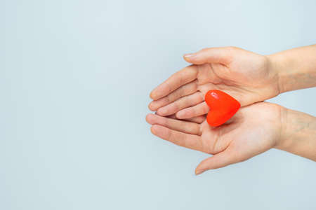 Female hands hold heart shape in palms on white background with copy space. Concept of heart disease and heart health care. St. Valentine's day conceptの写真素材