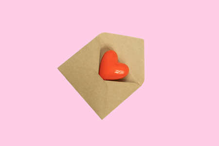Heart figure in a lteer envelope on pink background, top view. Concept of love correspondence,...