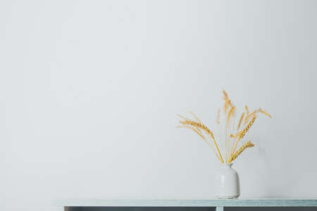 Spikelets or wheat in a vase on the table. Home decoration elements in sparse pastel backgroundの写真素材
