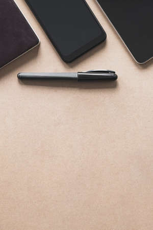 Business flat lay on brown paper background. Smartphone, tablet computer and notebook organizer on...
