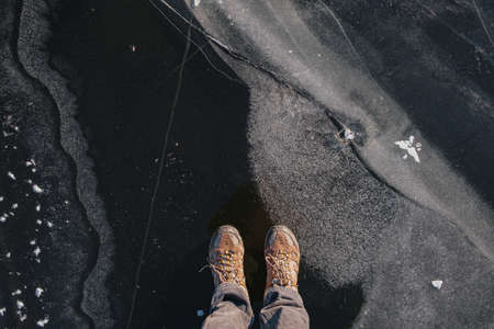 Standing on the thin ice, top view. Human feet on beautiful textured ice on the lake or riverの写真素材