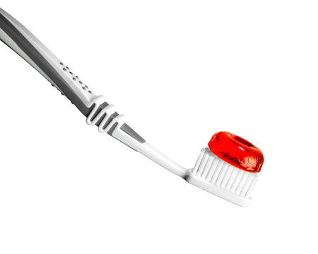 A toothbrush with red candy on it isolated on a white backgroundの写真素材