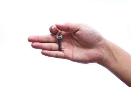 Silver key in a hand isolated on white. の写真素材