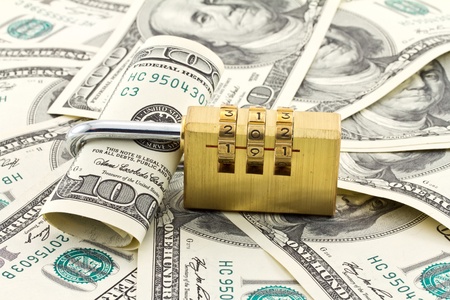 A combination padlock shot over stack of US Dollars banknotes 