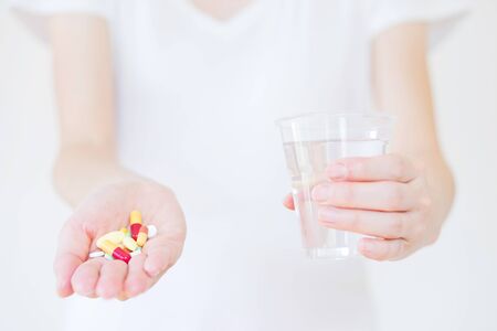 Hands with pills and glass of water isolated on whiteの写真素材