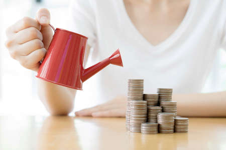 hand business woman and red watering can with moneyの写真素材