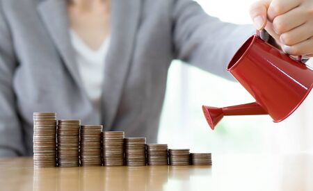 hand business woman and red watering can with moneyの写真素材