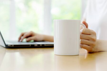 Close up of a woman hands typing in a laptop in a coffee shop terrace in the streetの写真素材