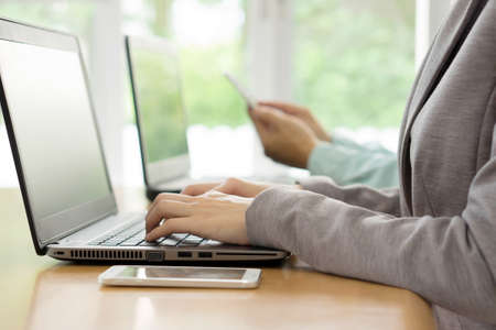 Young woman working in office, sitting at desk, using laptop