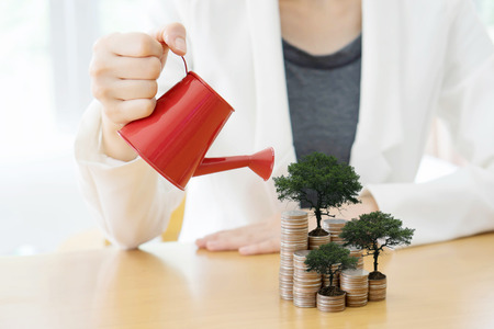 hand business woman and red watering can with moneyの写真素材