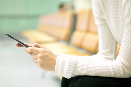 Woman at airport texting on a smartphone の写真素材