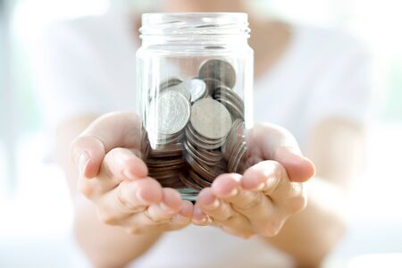 Woman holding money jar with coins close up