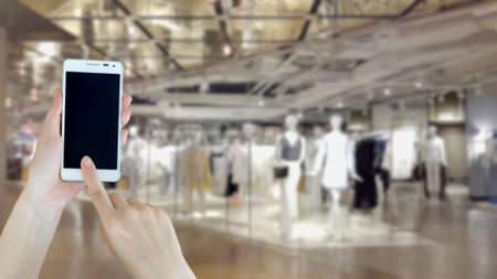 Woman using cellphone while shoppingの写真素材