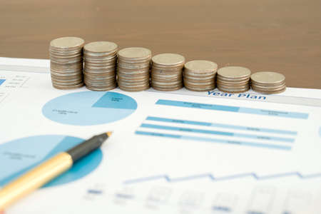 Business chart with paper clips, coins and pen
