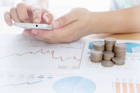 Businessman using smart phone with money coin and accounting graph