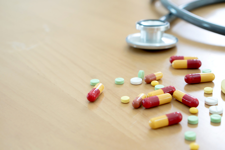 Medical concept with pills and stethoscope on table woodenの写真素材
