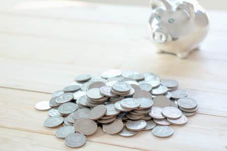 Coin is getting into piggy bank on table. Concept of saving moneyの写真素材