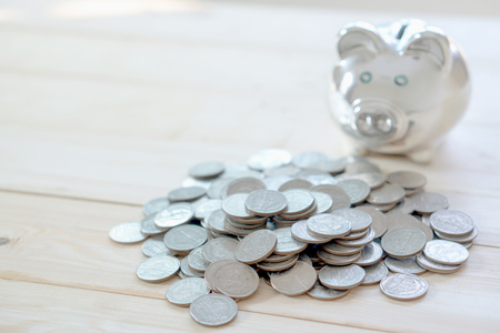 Coin is getting into piggy bank on table. Concept of saving moneyの写真素材