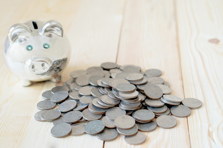 Coin is getting into piggy bank on table. Concept of saving moneyの写真素材