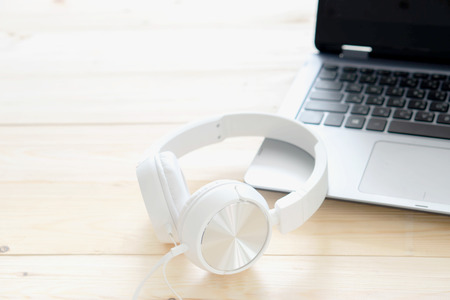 White headphone and laptop computer on wooden backgroundの写真素材