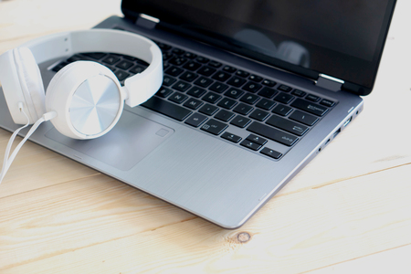 White headphone and laptop computer on wooden backgroundの写真素材