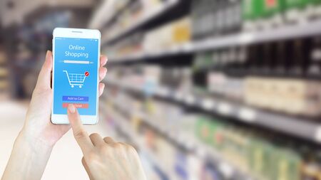 Woman using smart phon while shopping in supermarketの写真素材