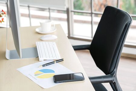 Business and workplace concept. Cup of hot coffee on work desk with computer keyboard Mobile and...