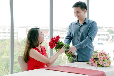 woman getting surprised with beautiful bouquet of roses by her boyfriend.
の写真素材