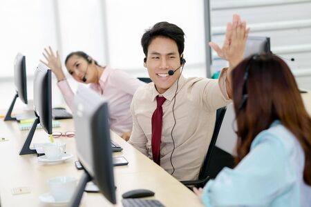 Call center team workers giving high five to each other at officeの写真素材