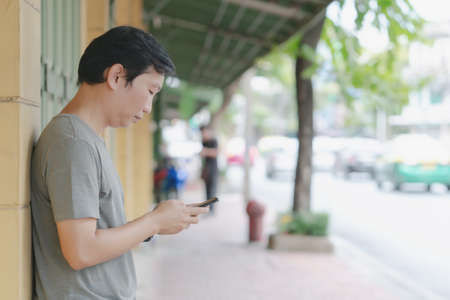 A Young men using smartphone in a city texting on his mobile phone.の写真素材