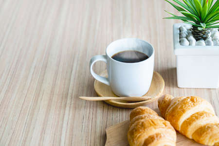 French breakfast: croissant bread and black coffee on table