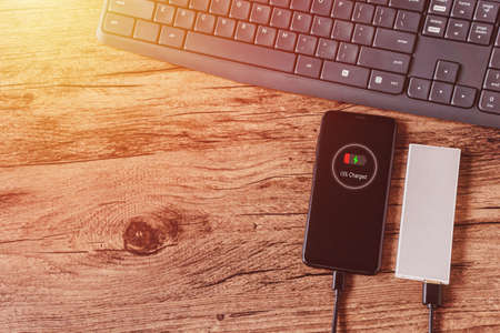 Charging of smart phone from power bank, lies on a wooden tableの写真素材