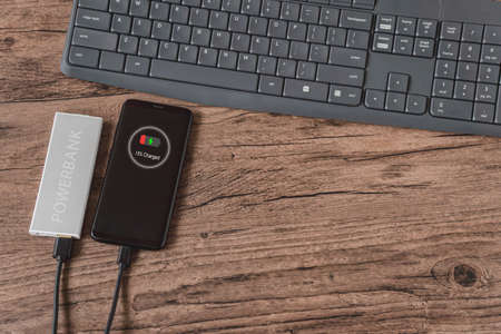 Charging of smart phone from power bank, lies on a wooden table