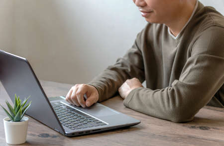 Young businessman sitting down and using his laptop to take a video call while working from homeの写真素材