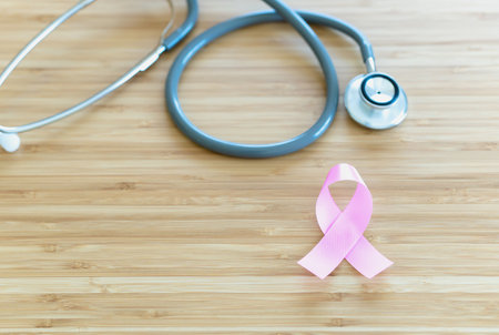 Pink ribbon and stethoscope on wooden table. Symbol of breast cancer, health care concept. Cancer dayの写真素材