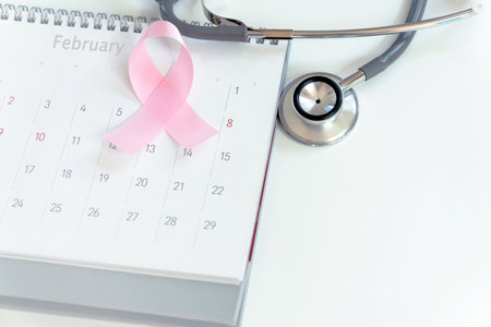 Cancer day concept : Pink ribbon symbol of breast cancer and calendar on black stone board backgroundの写真素材
