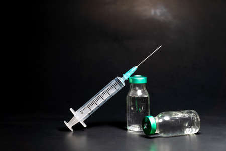 Potential trials stage concept on black background. Close up Vials with sterile needle syringe. Research and Development, Vaccination concept.の写真素材