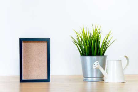 black square frames and green plant on wooden table, empty framesの写真素材