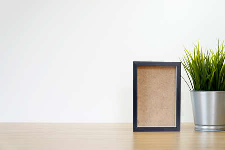 black square frames and green plant on wooden table, empty framesの写真素材