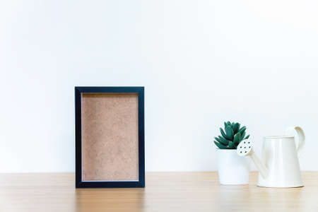 black square frames and green plant on wooden table, empty framesの写真素材
