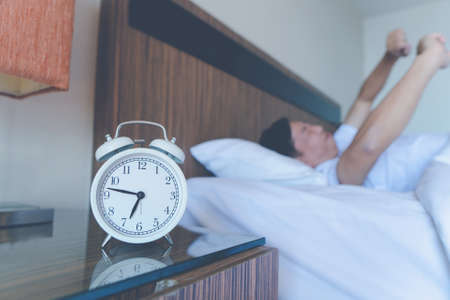 Young man stretching while waking up in the morning. Man yawning while waking up. Lazy young man in sleep. man yawns and stretches in bed.の写真素材