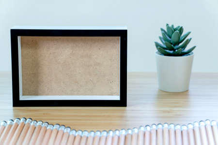 Black picture frame with pencil on a wooden table. design empty framesの写真素材