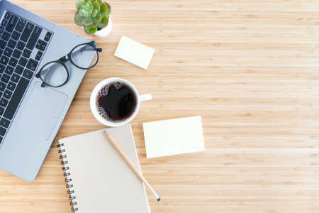 flat lay composition with notebook, pen, coffee, plant, laptop on wood background. Concept top viewの写真素材